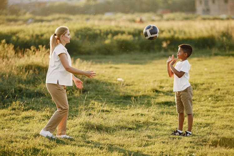 Parent and young child high-fiving after a youth sports game