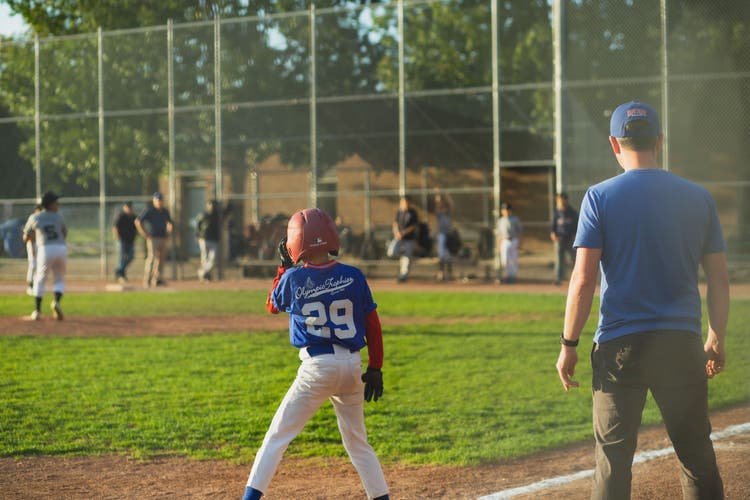 Youth baseball coach celebrating with players in the dugout